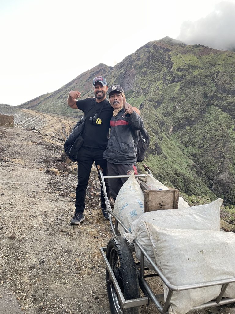 Majdi Alassaf with a sulfur miner beside a cart loaded with sacks of sulfur, Kawah Ijen